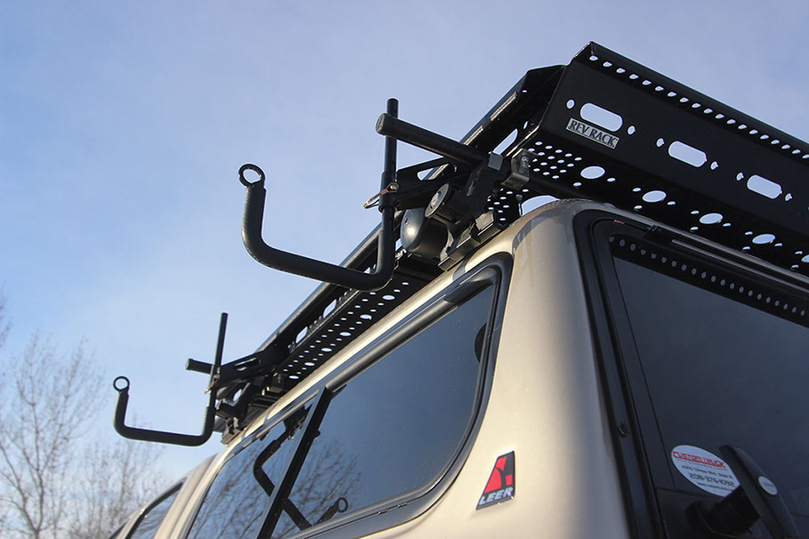 looking up at two adjustable revrack j hooks attached to a medium revrack tray atop a gold toyota tacoma with a gold topper shell and sky