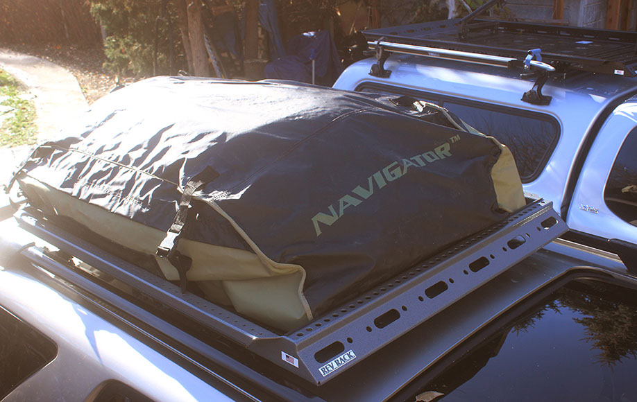 a weatherproof bag attached to small revrack tray atop a gold nissan pathfinder