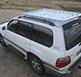 looking down at a medium white revrack tray atop a white toyota land cruiser with a foothill setting in the background
