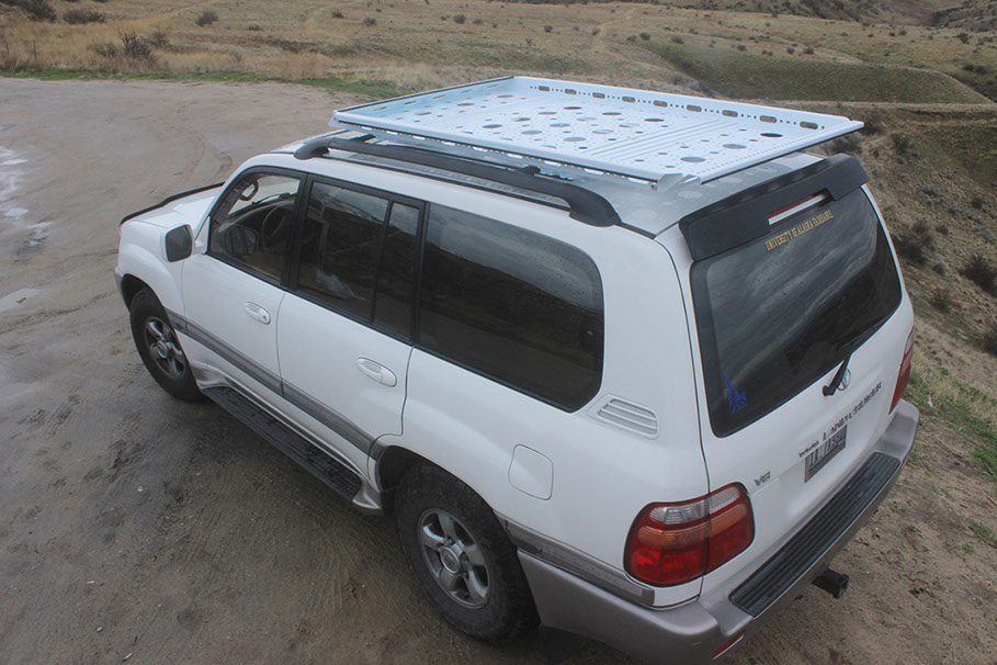 looking down at a medium white rev rack tray atop a white toyota land cruiser with a foothill setting in the background